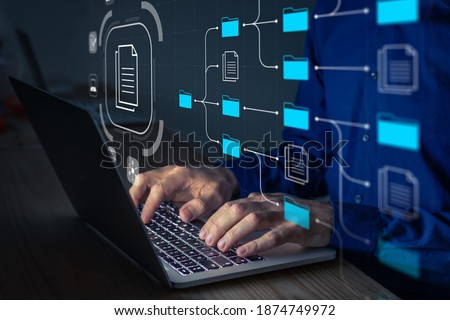 Document Management System (DMS) being setup by IT consultant working on laptop computer in office. Software for archiving, searching and managing corporate files and information. Business processes