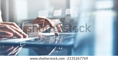Document Management System (DMS) being setup by IT consultant working on laptop computer in office with document directory. Software for archiving, searching and managing corporate file information Foto stock © 