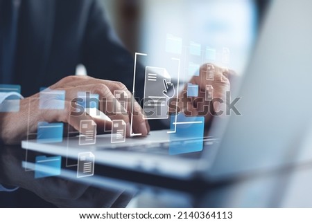 Document Management System (DMS) being setup by IT consultant working on laptop computer in office. Software for archiving, searching and managing corporate files and information