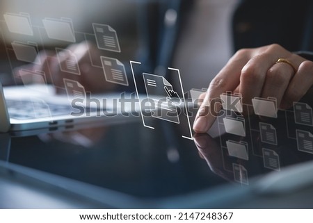 Document Management System (DMS) being setup by IT consultant working on laptop and tablet computer in office. Software for archiving, searching and managing digital files and information