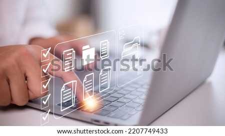 Document Management System (DMS) being setup by IT consultant working on laptop computer in office. Software for archiving, searching and managing corporate files and information