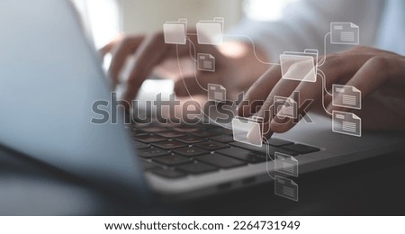 Document Management System (DMS) being setup by IT consultant working on laptop computer in office with document directory. Software for archiving, searching and managing corporate file information