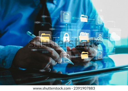 Document Management System (DMS) IT consultant working on laptop computer in office with document directory. Software for archiving, searching and managing corporate file information.