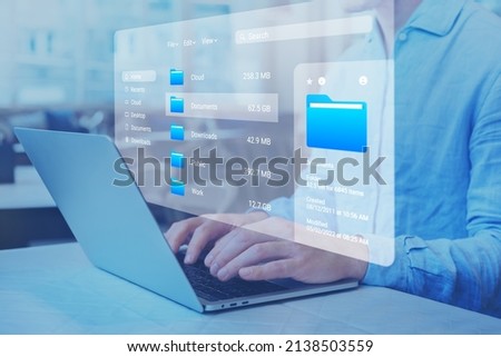 Document management system (DMS) and file manager used to browse folders on computer. Exploring directories on hard drive. Business data and process. Person working on laptop.