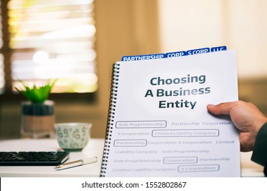 A document on different types of business formations being read by a small business owner while sitting in office desk. - Shutterstock ID 1552802867