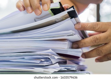 Document Report and business busy Concept: Asian Businessman hands working in many documents Stacks of folders in office for Annual Report files, Piles of unfinish sheet folder close annual budget.