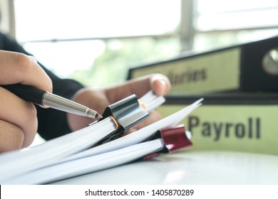 Document Report Or Business Management Concept: Businessman Manager Hands Holding Pen For Reading, Signing Paperwork Near Payroll Salary Binder, Work From Home And Learn Studying Prevent Covid-19