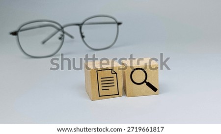 Document review and analysis concept with magnifying glass symbol on wooden blocks representing audit, inspection, compliance, and accuracy. 