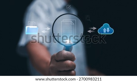 Document searching and digital data management concept. Hand holding magnifying glass show virtual document with cloud and folder symbol. Information retrieval and smart document storage systems.