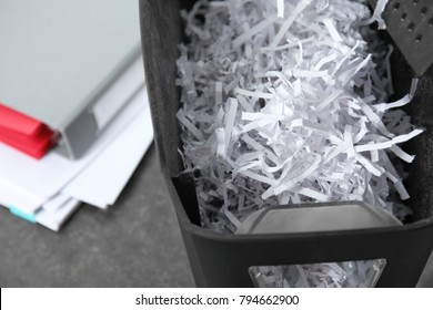 Document shredder with paper shreds on table, closeup
