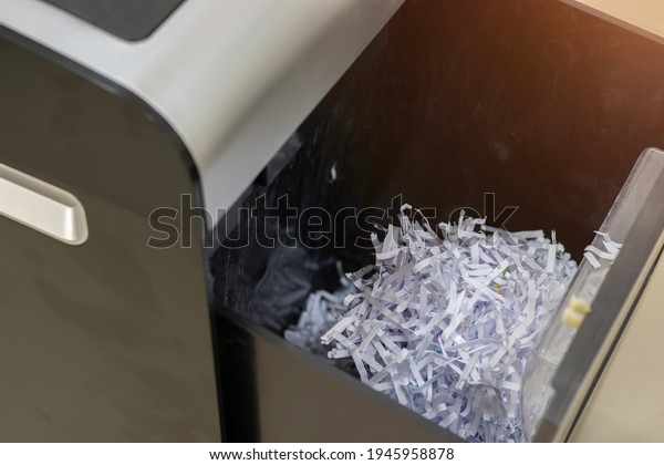 Document\
shredder with paper shreds on tray\
garbage.