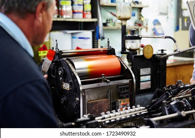 Documentary Photography Of A Commercial Printer: A Caucasian Male Employee Working In Front Of A Heidelberg Printer