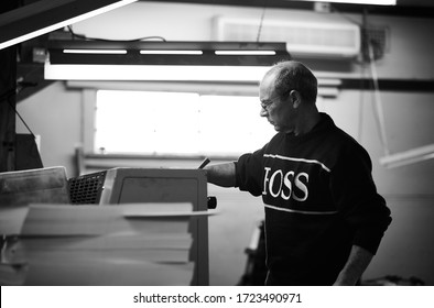 Documentary Photography Of A Commercial Printer: A Caucasian Male Employee Checking Work On A Heidelberg Offset Printer