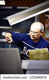 Documentary Photography Of A Commercial Printer: A Caucasian Male Employee Checking Work On A Heidelberg Offset Printer