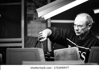 Documentary Photography Of A Commercial Printer: A Caucasian Male Employee Checking Work On A Heidelberg Offset Printer