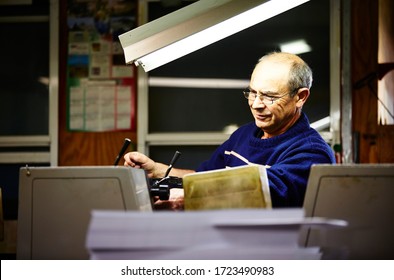 Documentary Photography Of A Commercial Printer: A Caucasian Male Employee Checking Work On A Heidelberg Offset Printer