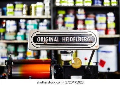 Documentary Photography Of A Commercial Printer: Detail Of A Heidelberg Printer With A Printing Workshop In The Background