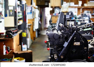 Documentary Photography Of A Commercial Printer: Detail Of A Heidelberg Printer With A Printing Workshop In The Background