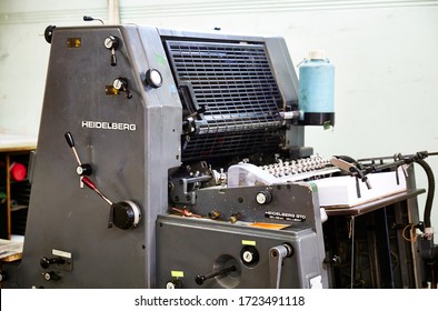 Documentary Photography Of A Commercial Printer: Detail Of A Heidelberg Printer With A Printing Workshop In The Background