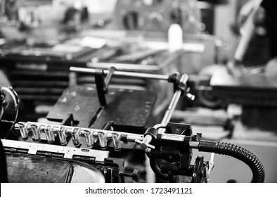 Documentary Photography Of A Commercial Printer: Detail Of A Heidelberg Printer With A Printing Workshop In The Background