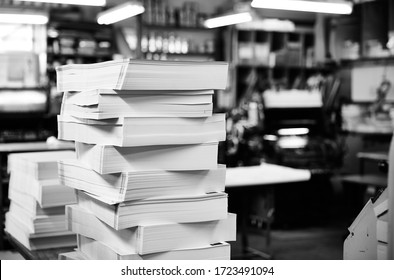 Documentary Photography Of A Commercial Printer: Finished Stacks Of Printed Work With A Printing Workshop In The Background