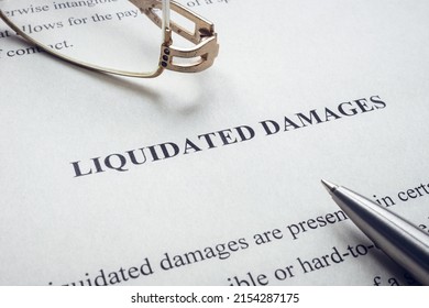 Documents About Liquidated Damages With Pen And Glasses.