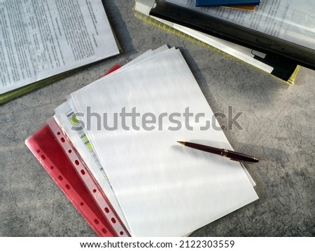 Documents in folders, blank sheets of paper, a pen are on the table. Blank sheet of paper. Workplace of a businessman, manager, scientist. The concept of drawing up, signing the contract.
