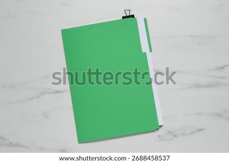 Documents in green folder with binder clip on white marble table, top view