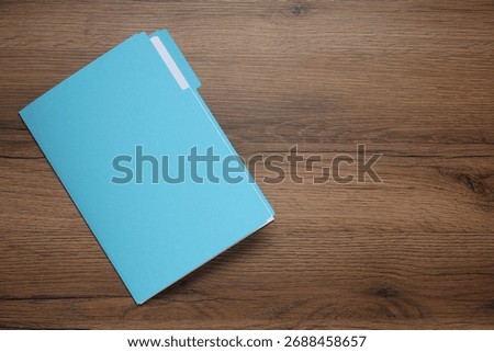 Documents in light blue folder on wooden table, top view. Space for text