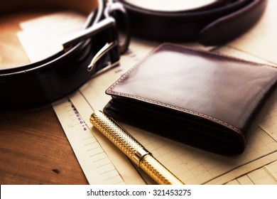 Documents, pen, belt and a leather wallet on a wooden desk. hotel table or gentleman's desk. shallow depth of field.
