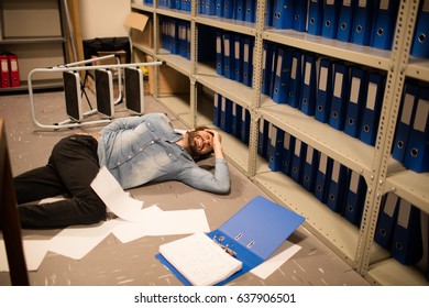 Documents scattered by fallen businessman in file storage room at workplace - Powered by Shutterstock