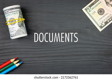DOCUMENTS - word (text) on a dark wooden background, dollars and colored pencils. Business concept (copy space).