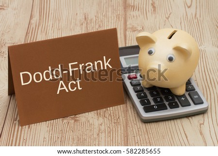 The Dodd-Frank Act, A golden piggy bank, card and calculator on a wood desk with text Dodd-Frank Act Foto stock © 