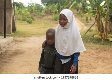 Dodoma, Tanzania. 08-18-2019. Lovely portrait of a muslim black girl taking care of her young brother at a rural school in Tanzania.