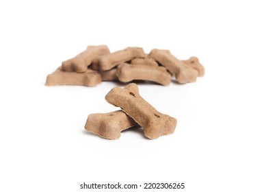 Dog Biscuits In Bone Shapes With Lamb. Isolated Chewing Bones In A Pile. Small Brown Or Beige Pet Food For Snacking, Training, Enjoyment Or Dental Hygiene. Selective Focus. White Background.