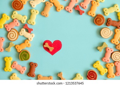 Dog Biscuits, Dog Snack Or Dog Treats And Red Heart In Center On Color Background, Can Use For Background, Advertising Product Food Or Pet Food.