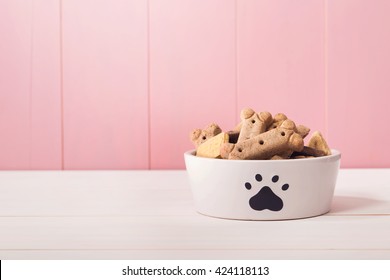 Dog food in a bowl filled with treats on wooden table - Powered by Shutterstock