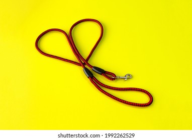 The Dog Leash Is Made Of Round Red And Black Nylon Rope. It Is Arranged In A Cute Heart Shape, Placed On A Yellow Background. Isolated.
