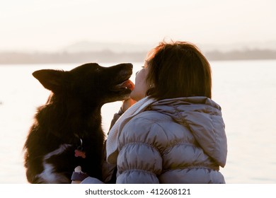 Dog Licking Mid Adult Womans Face On Lakeside