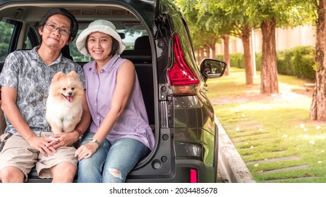 Dog With Owner Concept -  Asia Couple Family With Lovely Puppy Pomeranian Dog At The Back Of Suv Car On Travel Tip And Copy Space