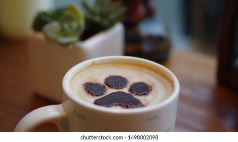 Dog paw latte art coffee in white mug on wood table at pet cafe - Powered by Shutterstock