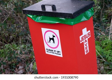  dog poo waste litter red bin with sign Clean it up no litter please and Jesus saves sign on the other side of the bin