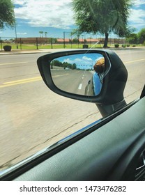 Dog In Rear View Mirror Sticking Nose Out Of A Car Window. 