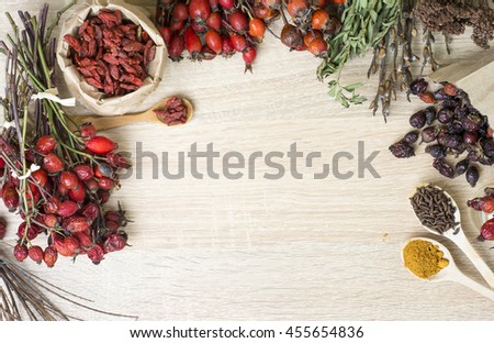 Dog roses and essential oil, bunch of dog rose, Herbal tea, Different types Rosa canina hips and hawthorn, dry goji berries, briar powder in wooden spoon. chinese herbal medicine selection in wooden