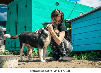 Dog at the shelter. Animal shelter volunteer takes care of dogs. Lonely dogs in cage with cheerful woman volunteer.  - Powered by Shutterstock