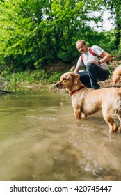 Dog Standing In Muddy Water With His Owner In The Background.