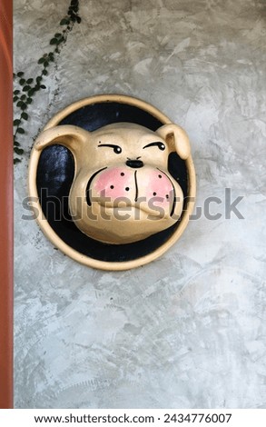 A dog statue leans out of a hole on concrete wall