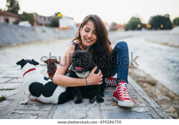 Dog walker with dogs enjoying outdoors next to city\
river. 