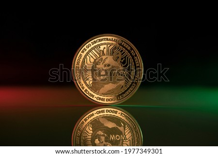 Doge cryptocurrency physical coin placed on reflective surface and lit with green and red lights