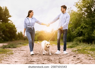 Dog-Friendly Date Concept. Two young people walking dog on a leash, looking at each other, holding hands
